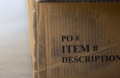 A cardboard carton printed with the headings PO number, item number and description.